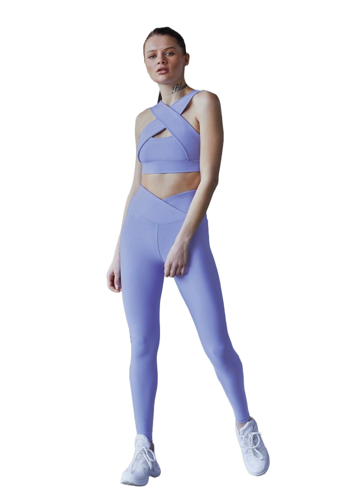 Einzelperson im schicken lila Neckholder-Outfit mit Lismina-Leggings und weißen Sneakers vor weißem Hintergrund.